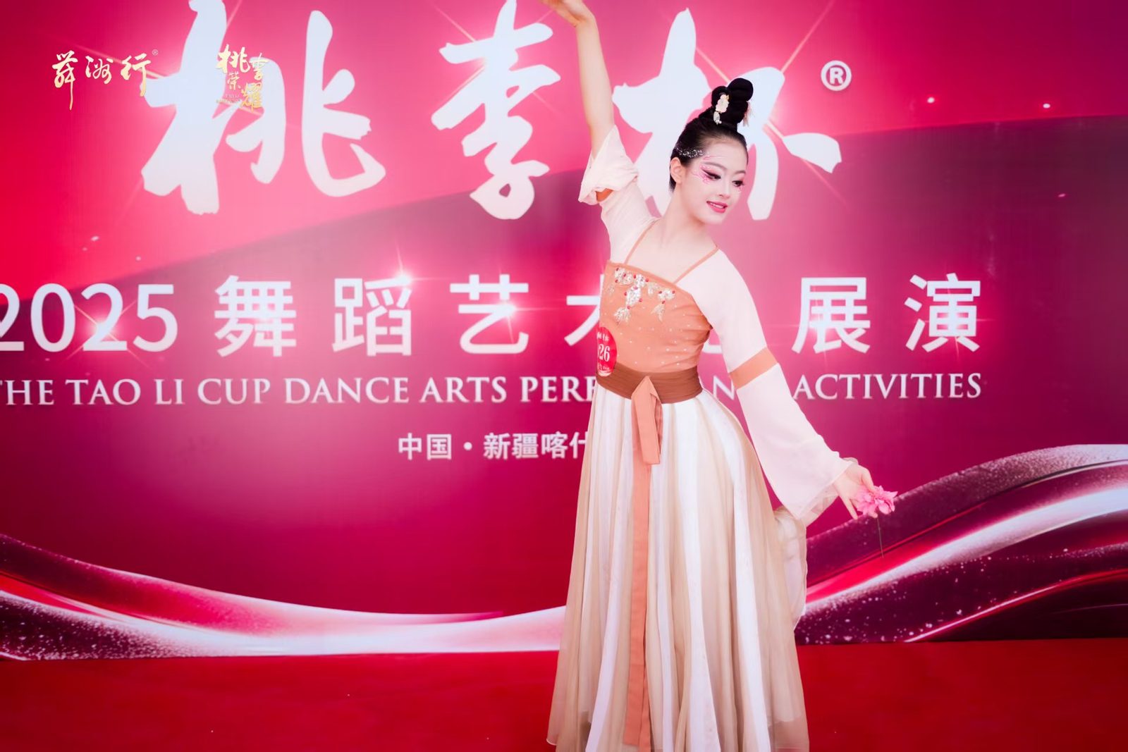 Joanna in costume on the Taoli Cup 2025 stage, one arm raised.